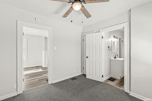 unfurnished bedroom featuring ensuite bathroom, sink, ceiling fan, and wood-type flooring