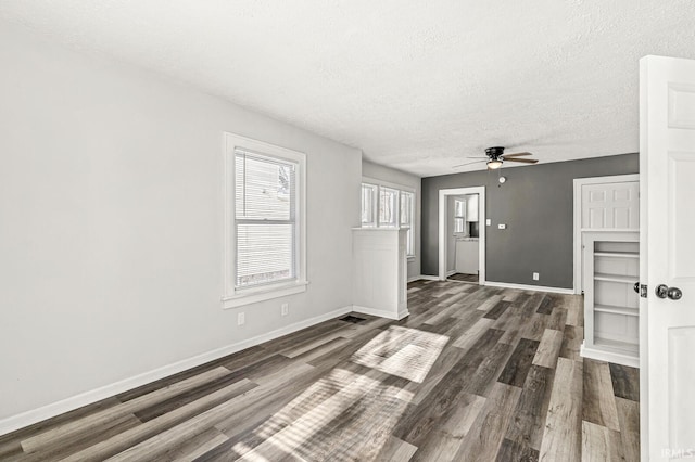 unfurnished living room featuring ceiling fan, dark hardwood / wood-style flooring, and a textured ceiling