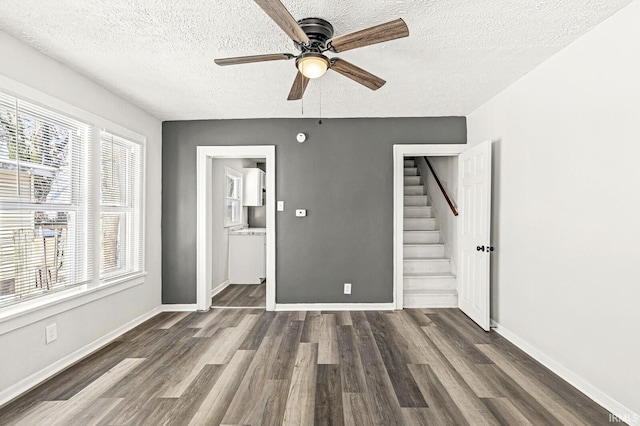 empty room with a textured ceiling, dark hardwood / wood-style floors, and plenty of natural light