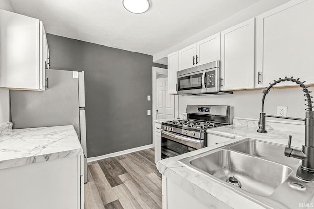 kitchen with light hardwood / wood-style floors, sink, white cabinetry, and stainless steel appliances