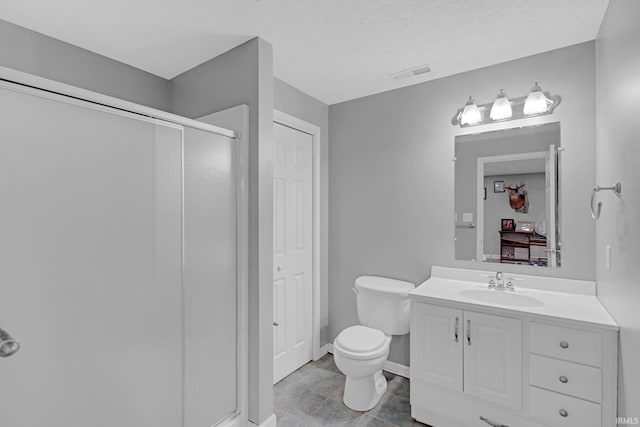 bathroom featuring vanity, toilet, an enclosed shower, and a textured ceiling