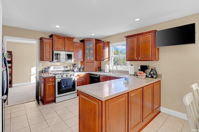 kitchen with light tile patterned flooring, sink, kitchen peninsula, and stainless steel appliances