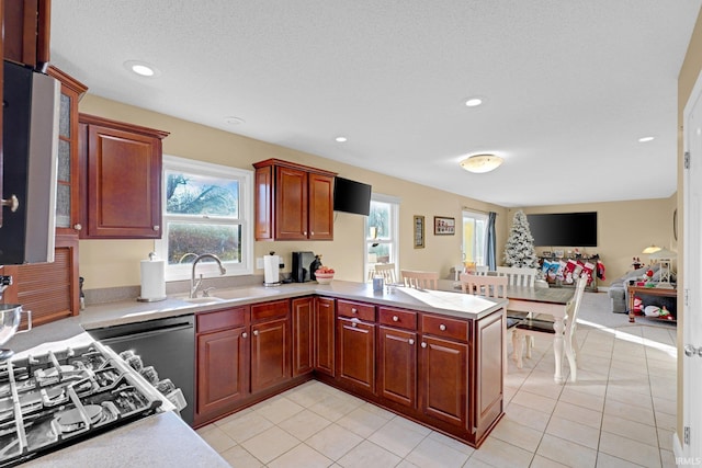 kitchen with kitchen peninsula, a textured ceiling, gas stovetop, sink, and light tile patterned flooring