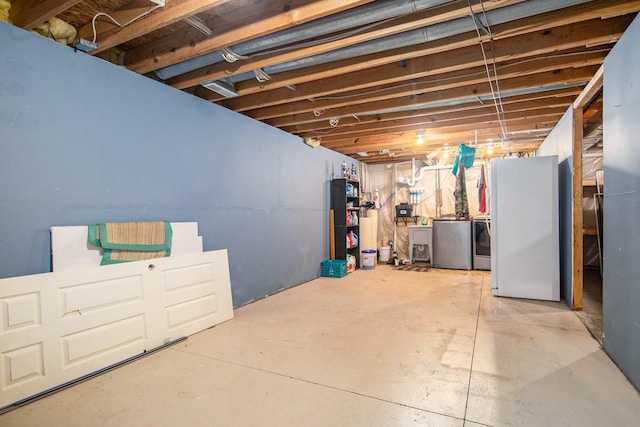 basement featuring washing machine and dryer and white fridge