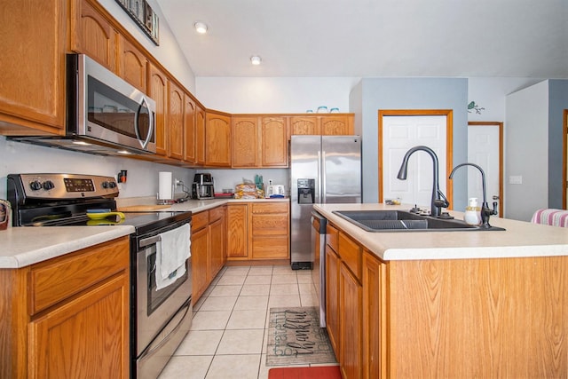 kitchen with appliances with stainless steel finishes, a center island with sink, light tile patterned floors, and sink