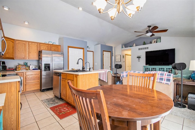 dining space with ceiling fan with notable chandelier, light tile patterned flooring, sink, and vaulted ceiling