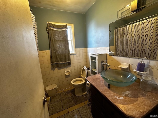 bathroom featuring vanity, tile walls, and toilet