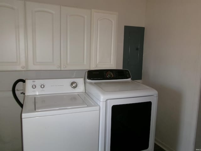 laundry room with electric panel, washer and clothes dryer, and cabinets