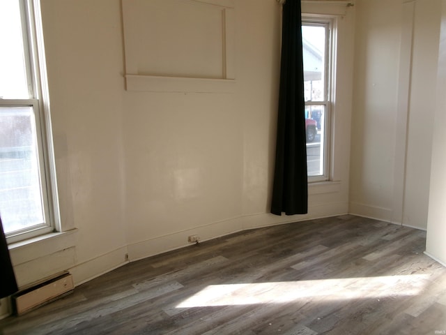 spare room featuring plenty of natural light, wood-type flooring, and a baseboard radiator