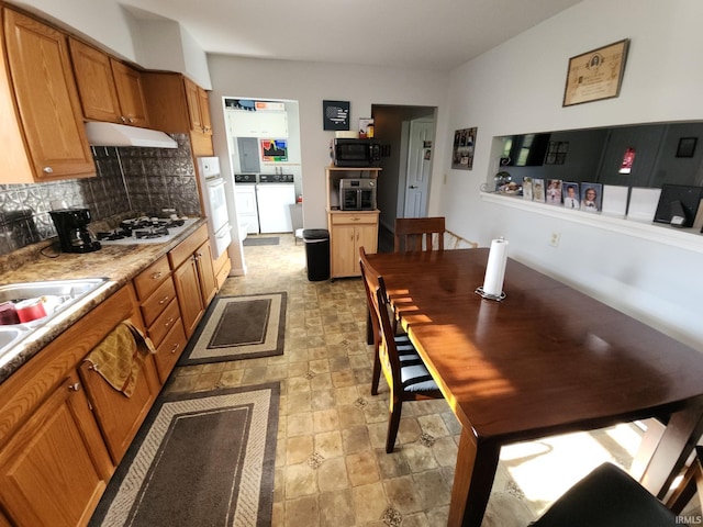 kitchen featuring washing machine and clothes dryer, white appliances, sink, and backsplash