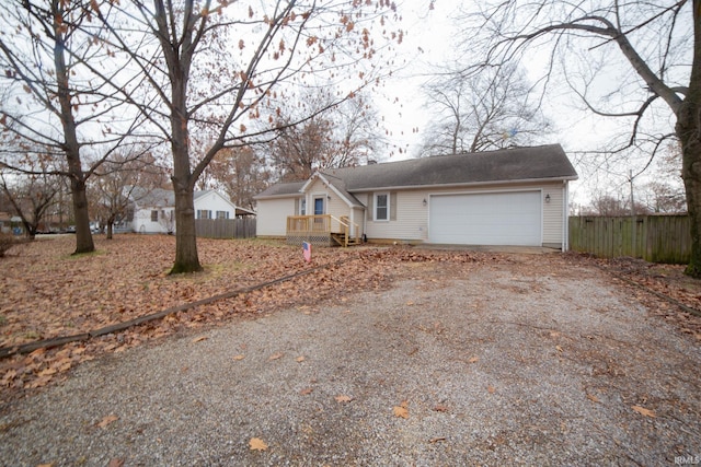 ranch-style house featuring an attached garage, fence, and dirt driveway