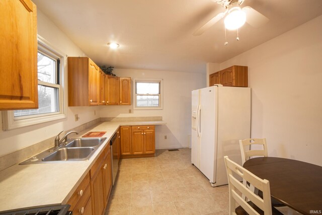 kitchen with a sink, light countertops, white fridge with ice dispenser, dishwasher, and range