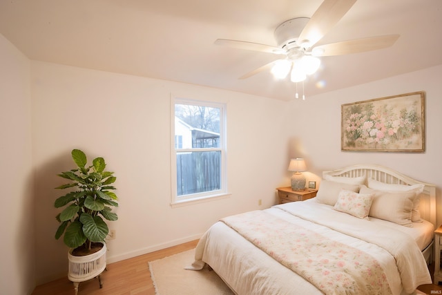 bedroom with a ceiling fan, wood finished floors, and baseboards