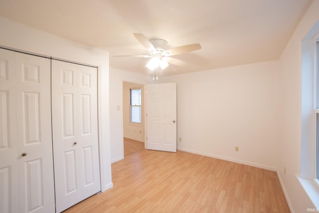 unfurnished bedroom featuring a closet, light wood-style flooring, baseboards, and ceiling fan