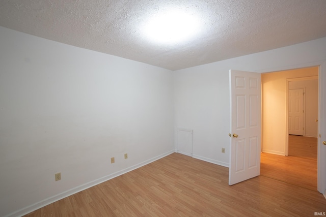 unfurnished room with baseboards, a textured ceiling, and light wood-style floors