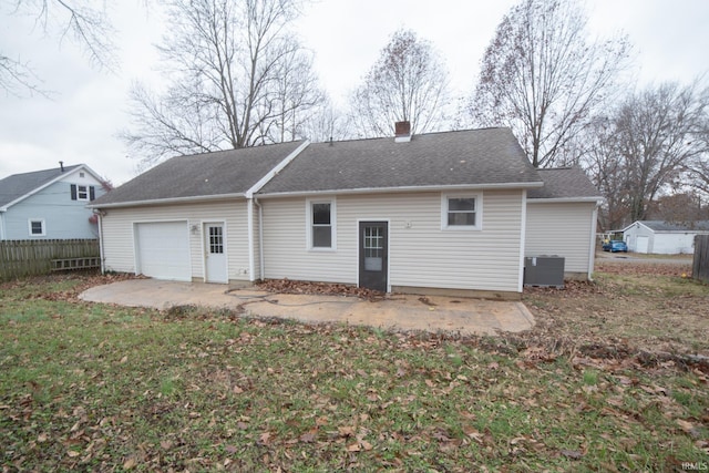 back of house with fence, roof with shingles, central AC, a chimney, and an attached garage