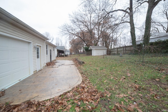 view of yard featuring an outbuilding, a storage unit, a garage, and fence