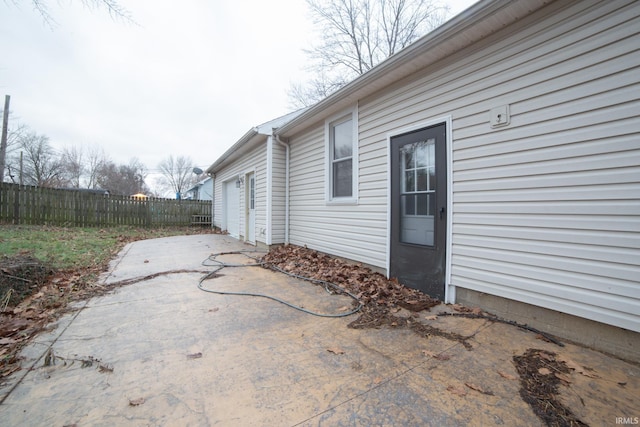 view of side of home with a patio, fence, and a garage