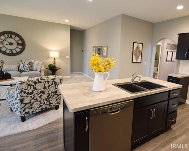 kitchen with stainless steel dishwasher, dark hardwood / wood-style flooring, sink, and a kitchen island with sink