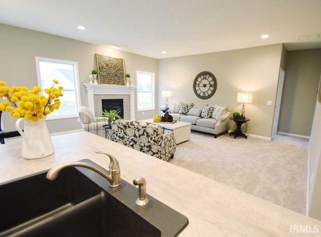 kitchen with light carpet, a tiled fireplace, and sink