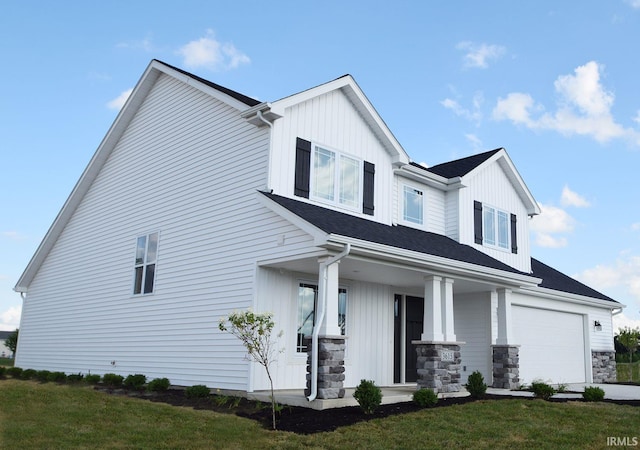 view of front of home featuring covered porch, a garage, and a front lawn