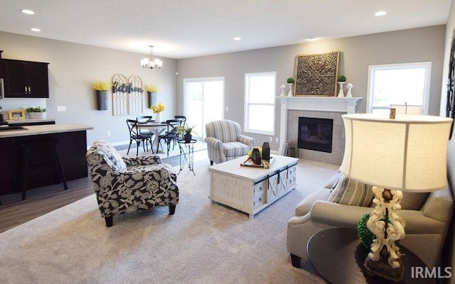 living room featuring a wealth of natural light, a fireplace, light wood-type flooring, and a notable chandelier