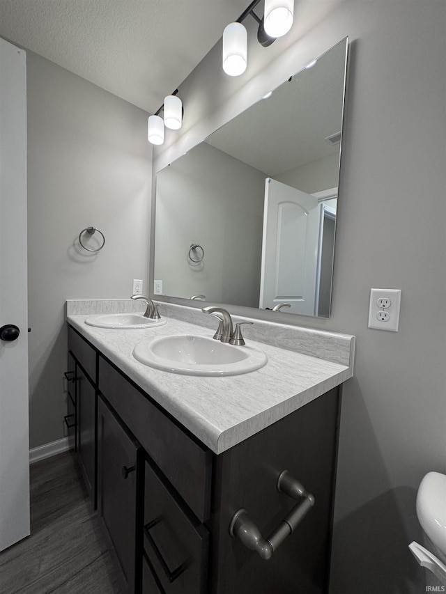 bathroom with toilet, hardwood / wood-style flooring, a textured ceiling, and vanity