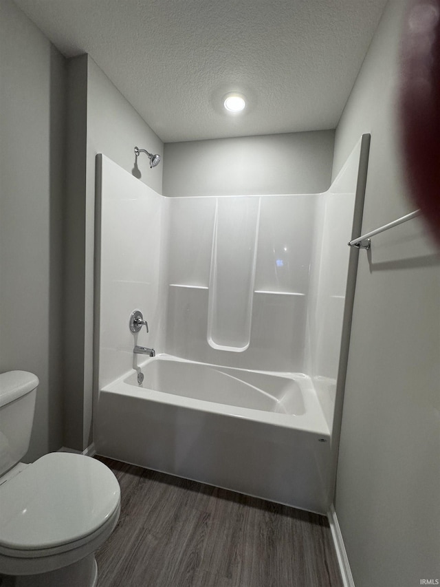 bathroom with shower / bathtub combination, hardwood / wood-style flooring, a textured ceiling, and toilet