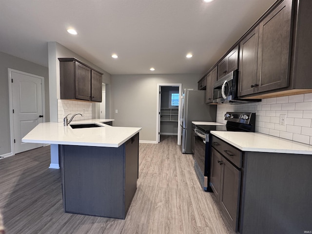 kitchen with sink, dark brown cabinetry, electric range, light wood-type flooring, and kitchen peninsula