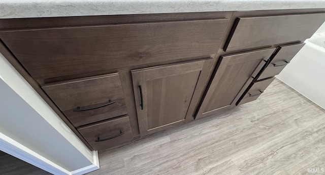 room details featuring dark brown cabinets and light wood-type flooring