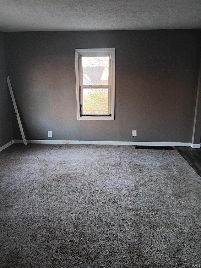 unfurnished room with dark colored carpet and a textured ceiling