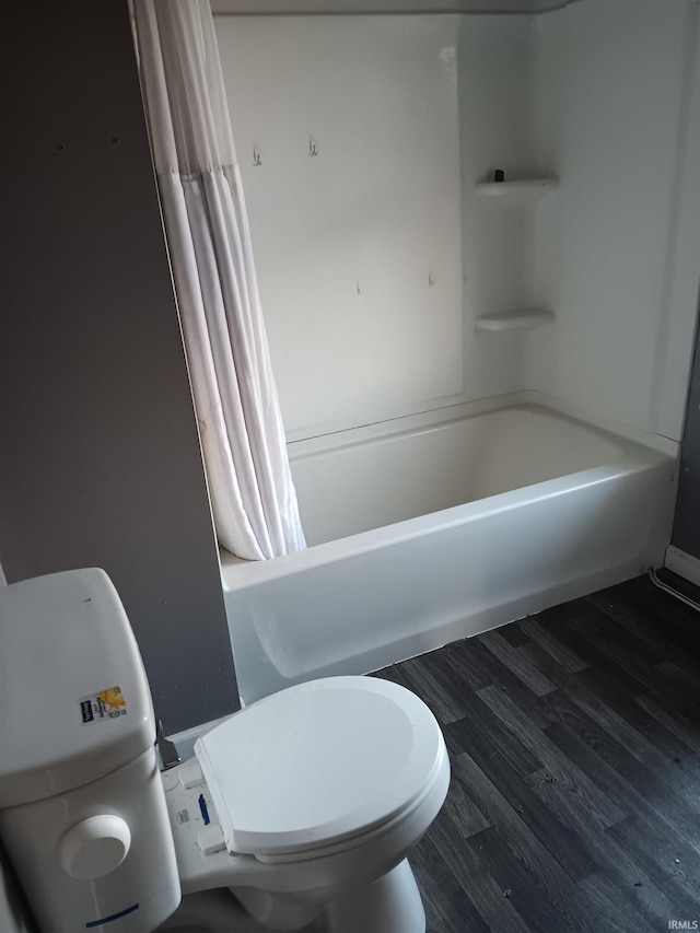 bathroom with hardwood / wood-style floors, toilet, and shower / bath combo with shower curtain