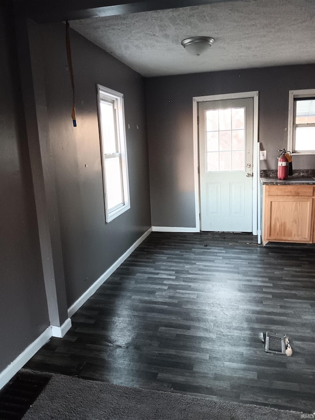 entryway with dark wood-type flooring and a textured ceiling