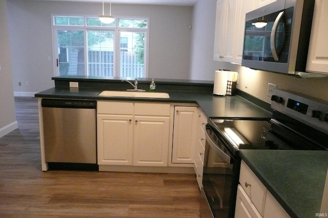 kitchen with appliances with stainless steel finishes, dark hardwood / wood-style flooring, sink, pendant lighting, and white cabinetry