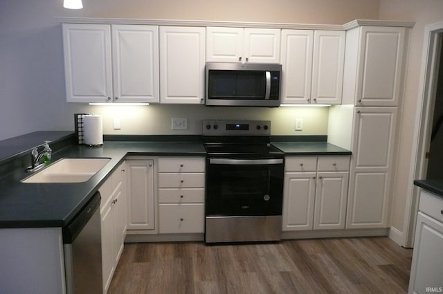 kitchen with dark hardwood / wood-style flooring, white cabinetry, sink, and appliances with stainless steel finishes