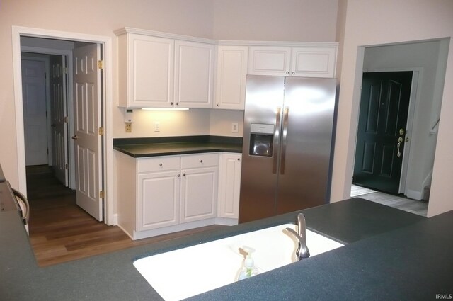 kitchen with hardwood / wood-style flooring, white cabinetry, and stainless steel fridge with ice dispenser