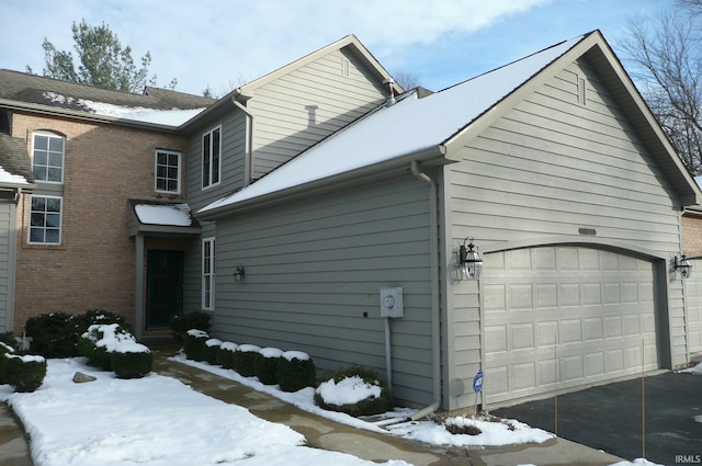 view of snowy exterior featuring a garage