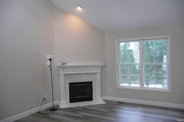 unfurnished living room with a tile fireplace, hardwood / wood-style flooring, and lofted ceiling