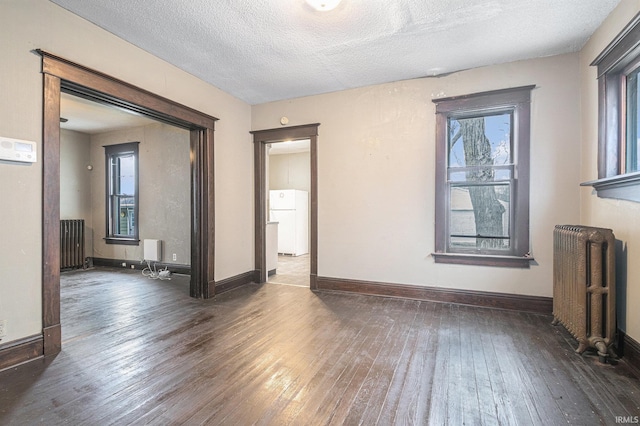 empty room with radiator heating unit, dark hardwood / wood-style flooring, and a textured ceiling