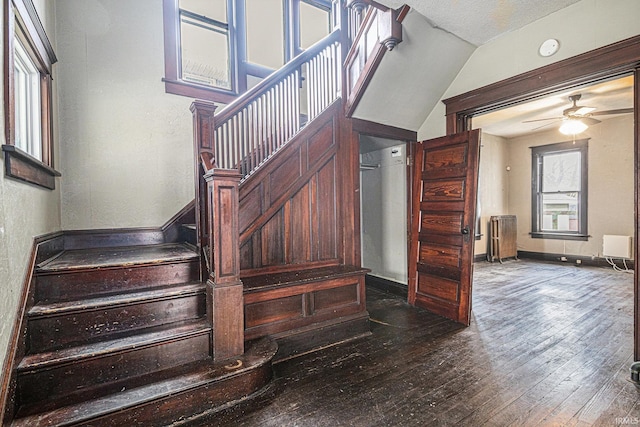 staircase featuring radiator, ceiling fan, vaulted ceiling, a textured ceiling, and hardwood / wood-style flooring