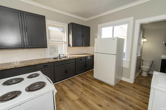 kitchen featuring white appliances, backsplash, sink, light hardwood / wood-style floors, and washer / dryer