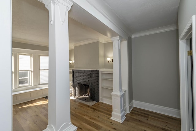 living room featuring ornate columns, wood-type flooring, crown molding, and a brick fireplace