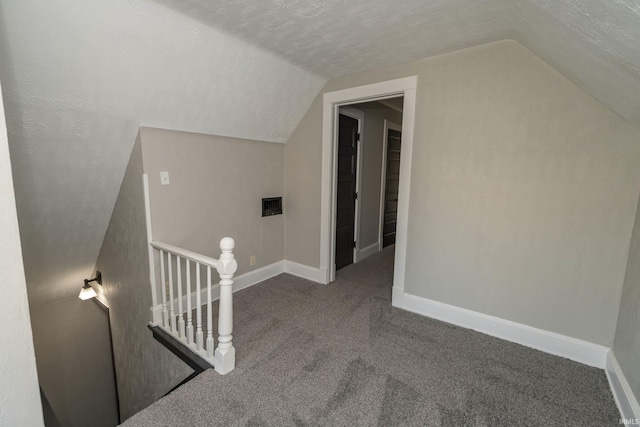 additional living space with a textured ceiling, carpet floors, and vaulted ceiling