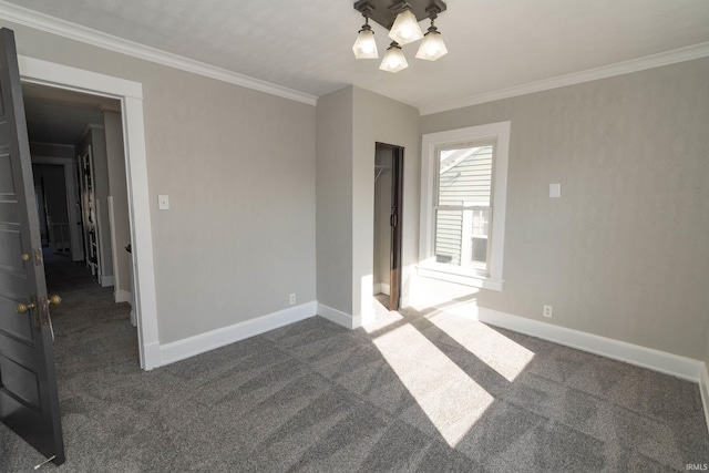 empty room with dark carpet, ornamental molding, and a chandelier