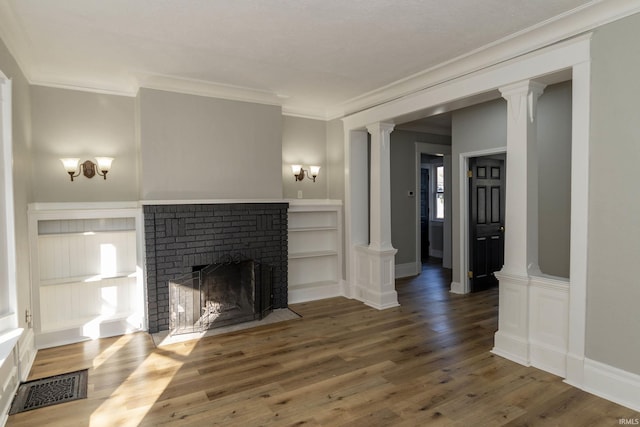 unfurnished living room with wood-type flooring, ornamental molding, and a brick fireplace