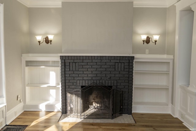 interior details with built in shelves, hardwood / wood-style floors, ornamental molding, and a brick fireplace