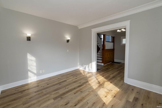 spare room featuring crown molding, wood-type flooring, and a notable chandelier