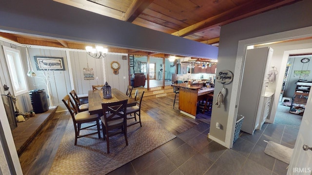 dining area with beamed ceiling, dark tile patterned flooring, an inviting chandelier, and wooden ceiling