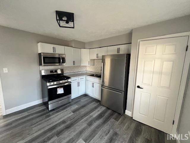 kitchen with decorative backsplash, white cabinetry, dark wood-type flooring, and appliances with stainless steel finishes