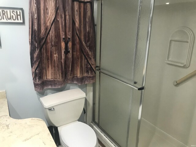 bathroom with toilet and a shower with door